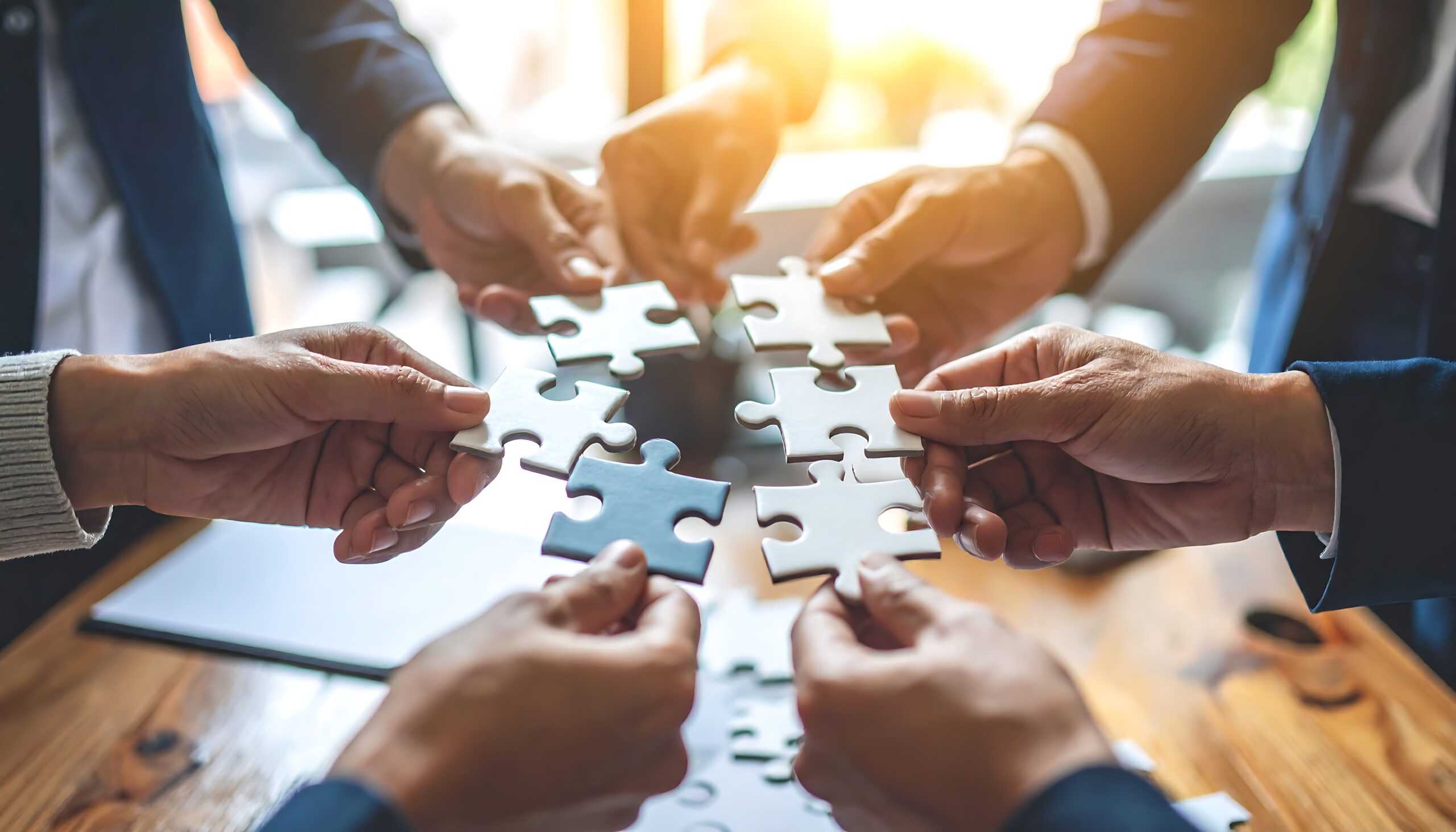 Mehrere Personen fügen gemeinsam Puzzleteile zusammen als Symbol für ein erfolgreiches Beteiligungsmanagement.